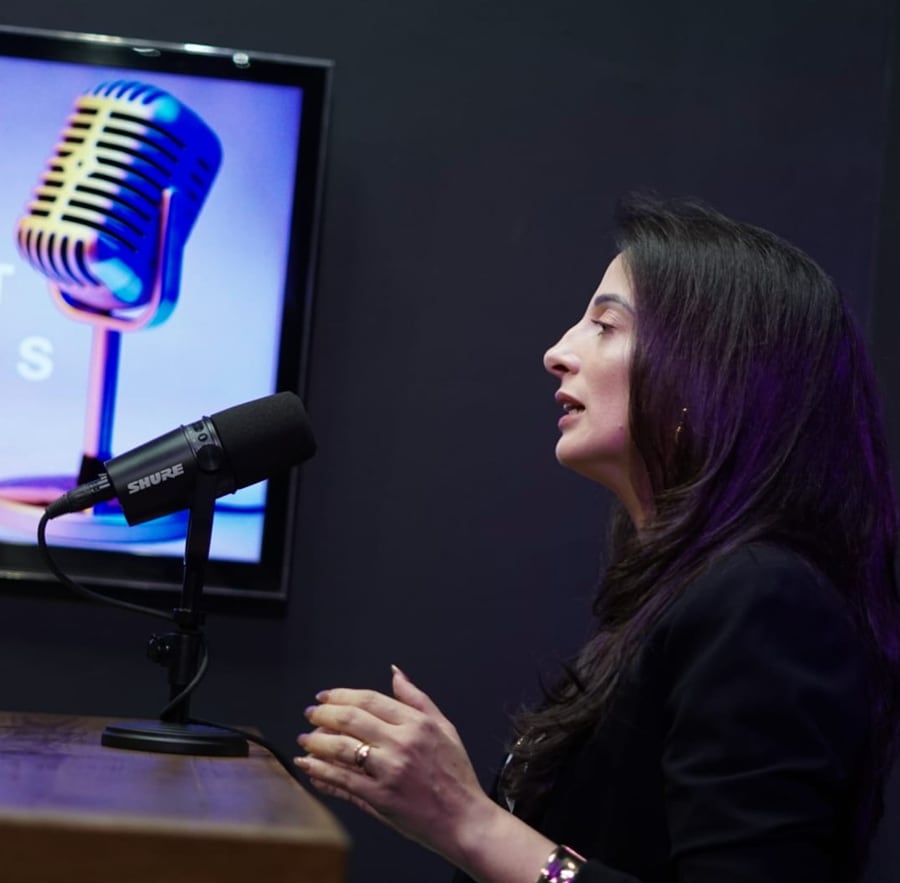 Jéssica Marcelli participando de uma gravação de podcast diante de um microfone