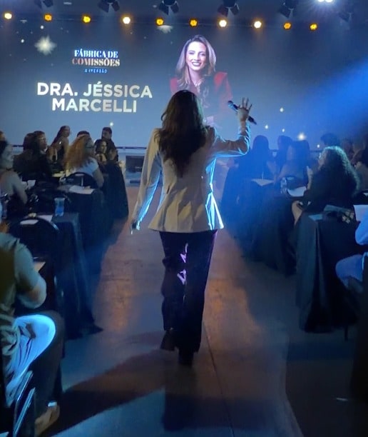 Jéssica Marcelli caminhando em direção ao palco durante uma palestra